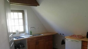 A compact kitchen with wooden cabinets, a built-in sink, and a small refrigerator. - APARTMENT BETWEEN SKY AND MOUNTAINS (Cruet)