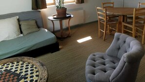 A cozy room with a loft bed, a round table with chairs, a potted plant, and a large window with curtains. - APARTMENT BETWEEN SKY AND MOUNTAINS (Cruet)