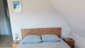 A neatly made bed with a light blue bedspread, two pillows, and three folded towels. - APARTMENT BETWEEN SKY AND MOUNTAINS (Cruet)