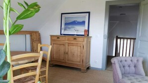 A cozy room with a wooden dining table, a cushioned chair, a potted plant, a wooden cabinet, and a framed picture on the wall. - APARTMENT BETWEEN SKY AND MOUNTAINS (Cruet)