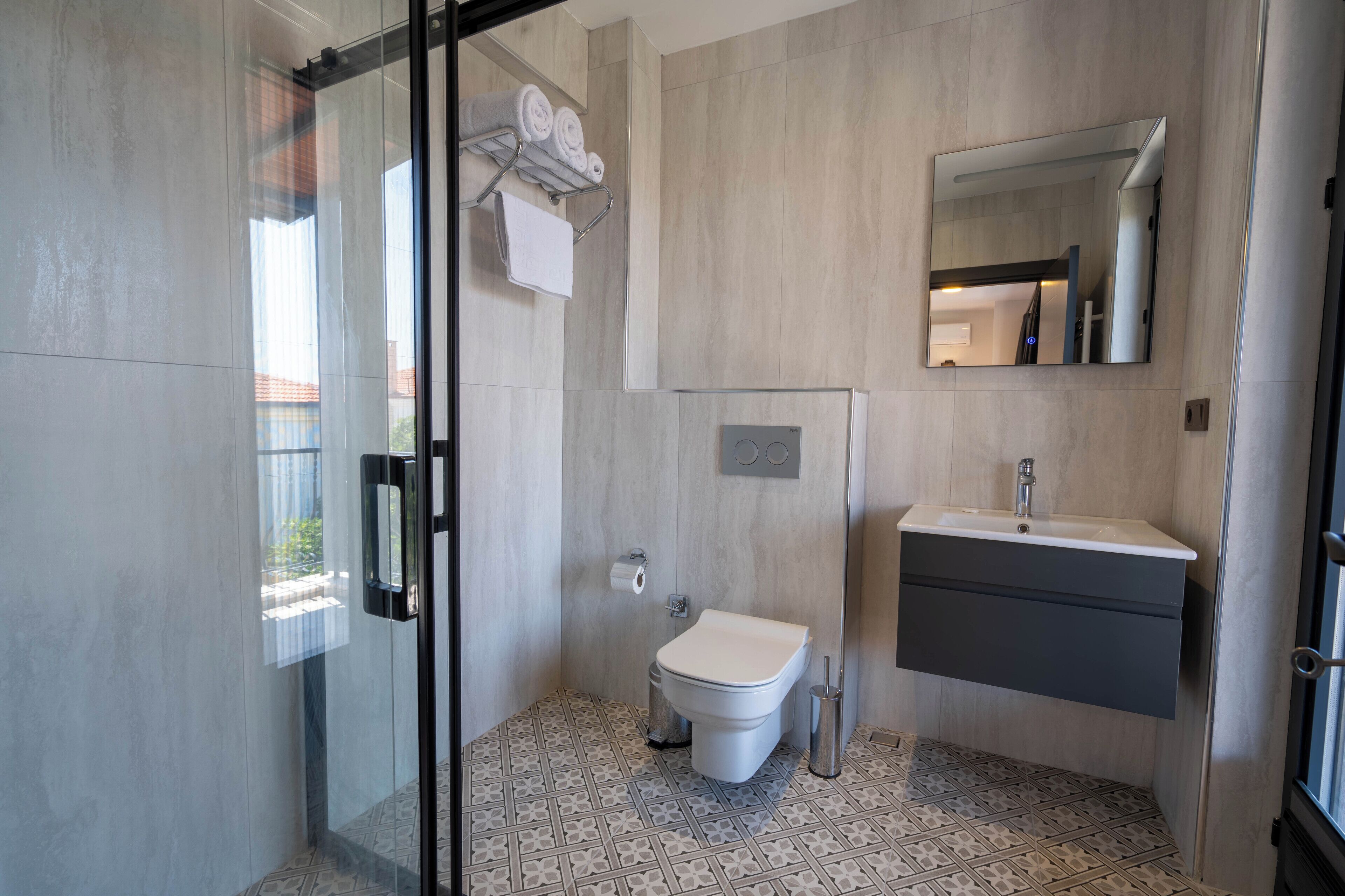 Ein modernes Badezimmer mit Duschkabine aus Glas, Toilette, Waschbecken und Spiegel.
