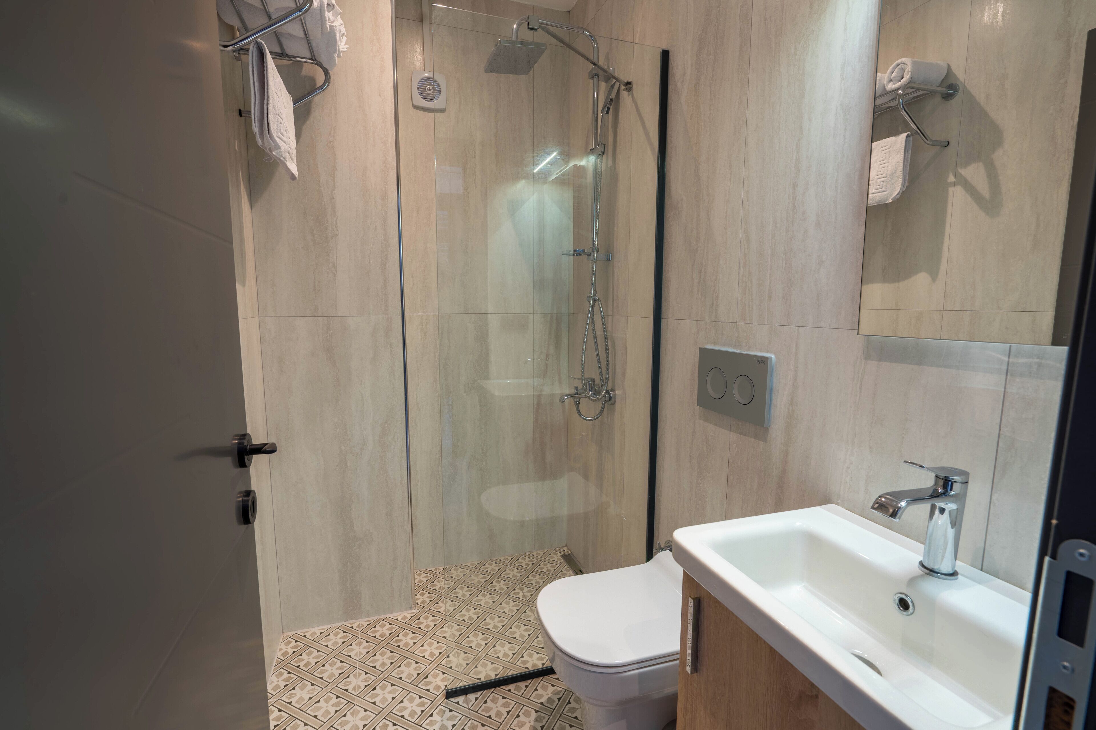 A modern bathroom with a glass-enclosed shower, a white sink, and a toilet.