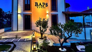 A two-story building with the name "BAPS GUNDA" illuminated on the facade. - BAPS Cunda (Ayvalik)
