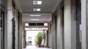 A corridor with a patterned floor, concrete walls, and a door at the end leading to a room with a plant. - The Little Etruscan, cozy tourist rental in the center of Arezzo (Arezzo)
