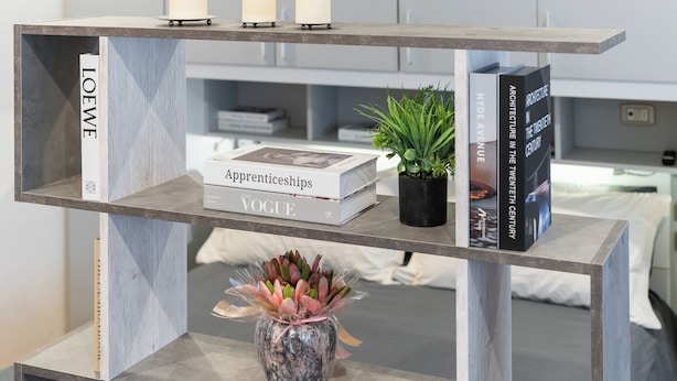 A modern, multi-tiered bookshelf with books, candles, and a potted plant. - The Little Etruscan, cozy tourist rental in the center of Arezzo (Arezzo)