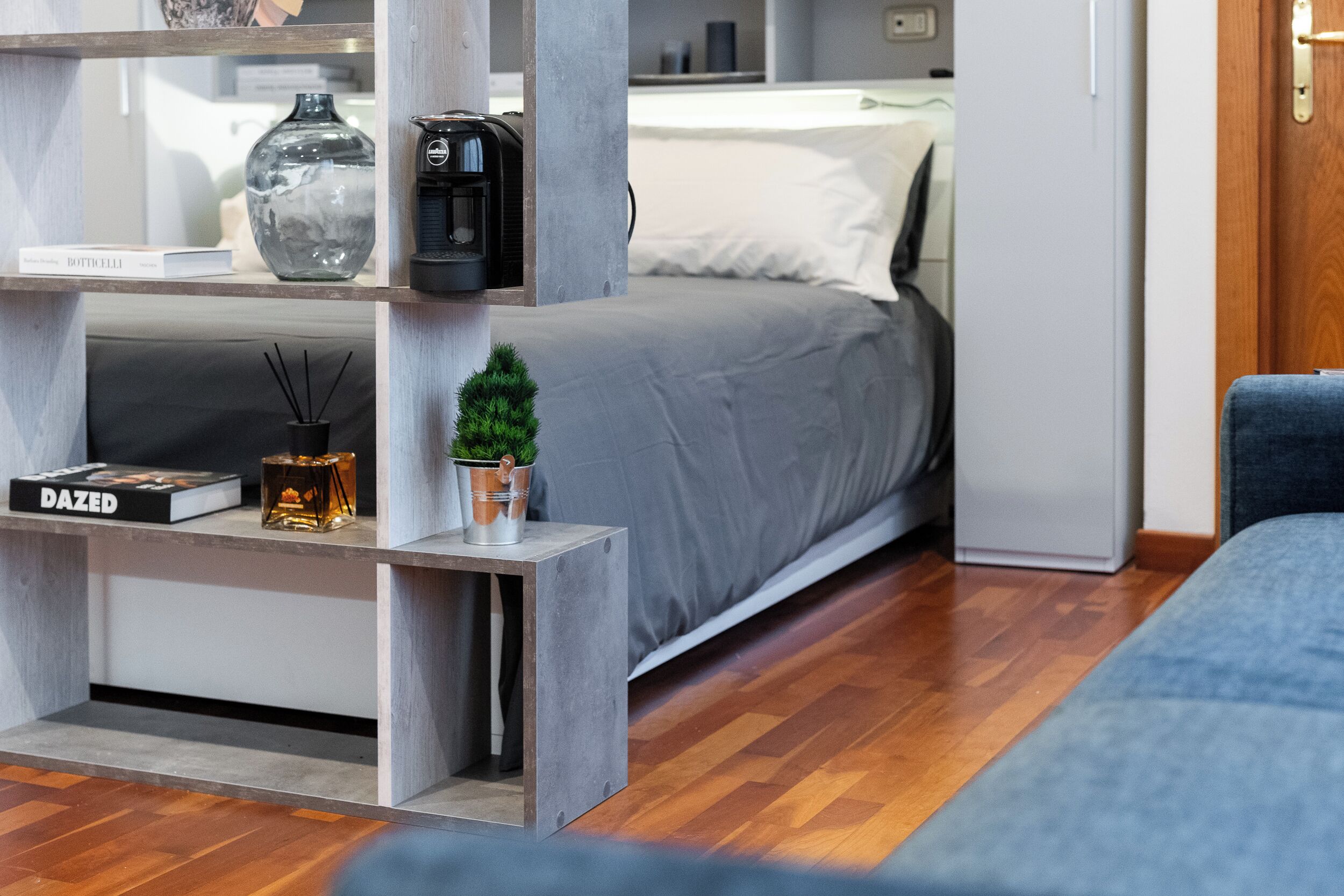 A modern bedroom with a bed, bedside table, and a small potted plant.