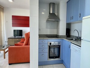 Cocina compacta con horno empotrado, microondas y extractor de acero inoxidable.