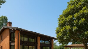 Ein modernes Haus mit großer Glasfassade, einem Schotterweg und einer Pergola mit Sitzgelegenheiten.