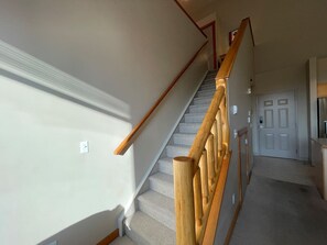 A staircase with wooden handrails and carpeted steps leading to a door.