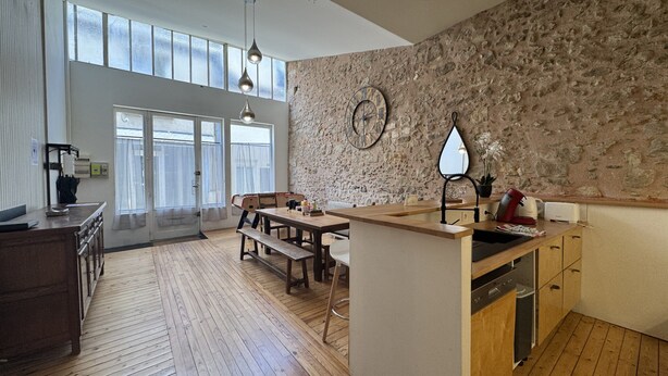Una cocina amplia con piso de madera, una isla central y una pared de acento de piedra.
