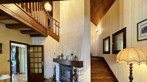 Una majestuosa escalera con detalles de madera, una chimenea con marco de piedra y un candelabro.