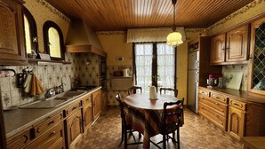 Una cocina con armarios de madera, una mesa de comedor y un suelo de baldosas hexagonales.