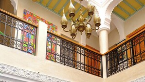 A spacious interior with a high ceiling, ornate metal railings, and a chandelier. - Riad Rose Mati (Marrakech)