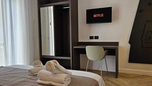 Een hotelkamer met een bed, een bureau, een stoel, een televisie en een grote spiegel.