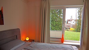Une chambre à coucher avec un lit, une table de chevet avec une lampe et une fenêtre avec des rideaux.