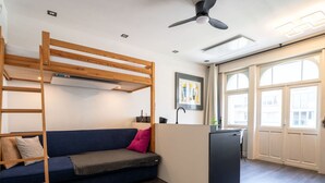 Een moderne kamer met een stapelbed, een slaapbank, een bureau en een groot raam.