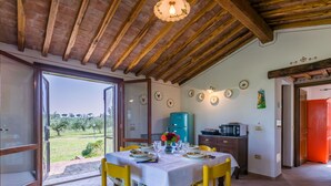 A dining area with a table set for two, a blue refrigerator, and a red door in the background. - Stunning private villa for 5 people with A/C, WIFI, private pool, TV, patio and panoramic view (Bibbona)