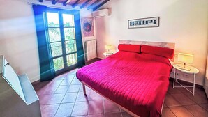 A bedroom with a large bed, a window, a radiator, and a framed picture on the wall. - Cosy apartment for 5 guests with WIFI, A/C, terrace and pets allowed (Guardistallo)