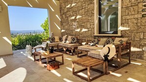 A sunlit patio with a stone wall, a large window, and outdoor furniture. - Beautiful private villa for 24 guests with WIFI, private pool, A/C, TV and patio (Stroncone)