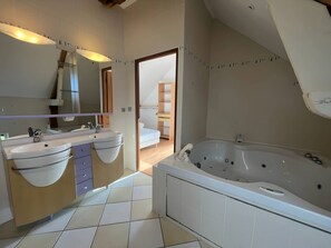 Un baño moderno con dos lavamanos, una bañera amplia y una ducha a ras de suelo.