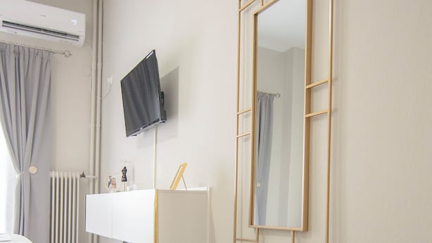 Een moderne badkamer met een witte wastafel, een grote spiegel, een plant in pot en een radiator.