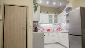 Een moderne keuken met witte kasten, een roestvrijstalen koelkast en een houten deur.