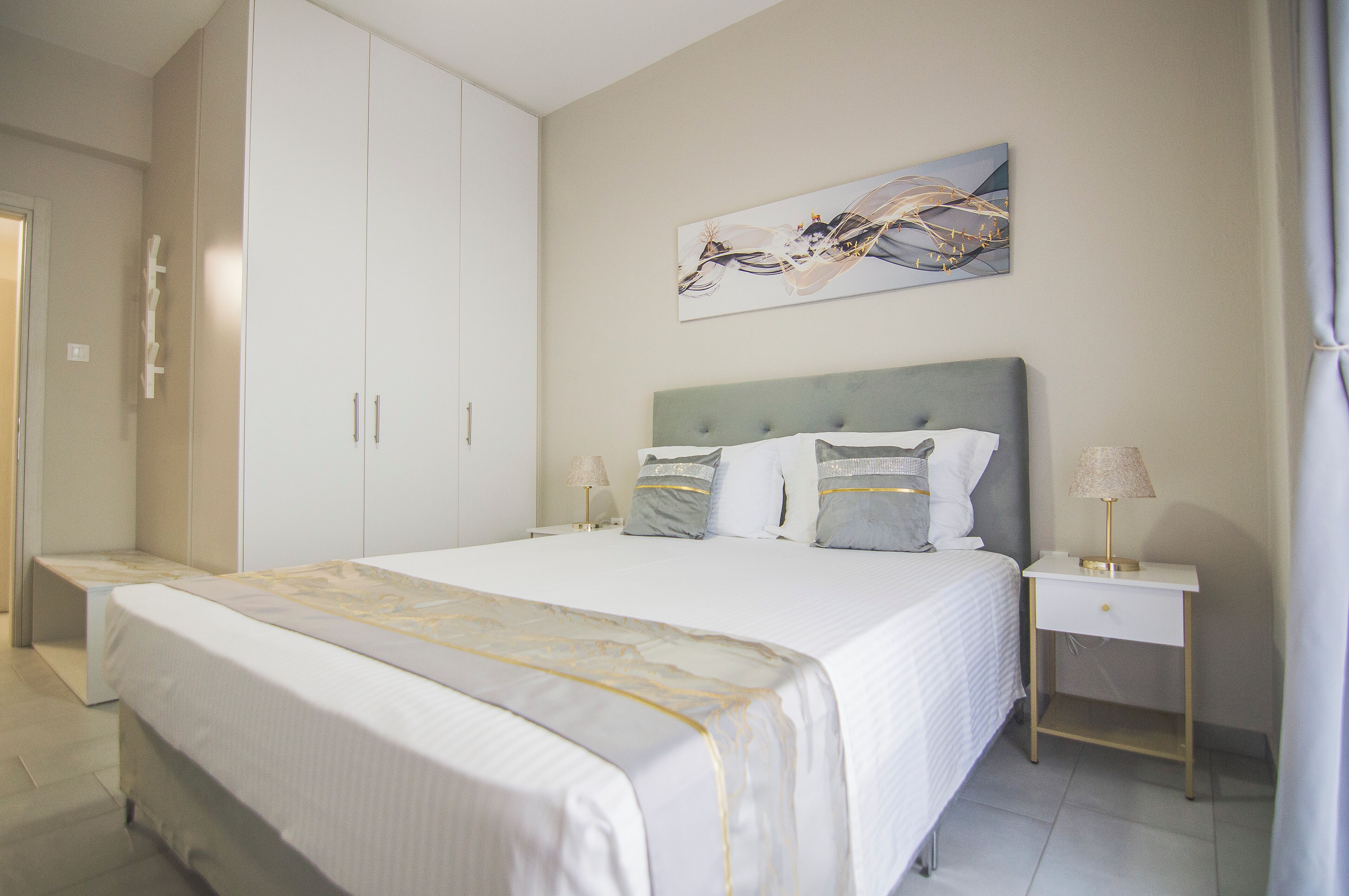 Ein ordentlich eingerichtetes Schlafzimmer mit einem großen Bett, einem Nachttisch, einem Beistelltisch und einem Kleiderschrank.