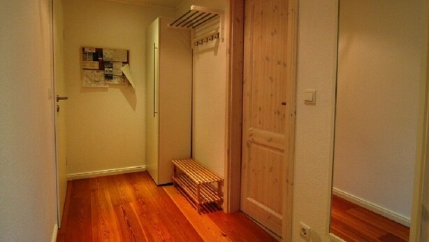 A narrow hallway with wooden flooring, a wooden door, and a bench. - Hamburg Wedel Apartment NORDLICHT on the Elbe (Wedel)