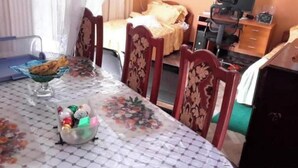 A dining table with a floral tablecloth, a bowl of fruit, and a floral chair design. - Birhan Guest House (Addis Ababa)