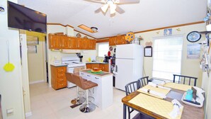 Una cocina compacta con armarios de madera, una isla central y una zona de comedor con mesa y sillas.