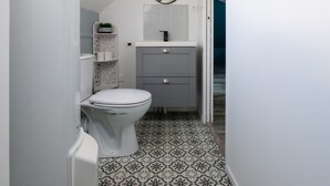 A compact bathroom with a toilet, a sink, and a mirror. - Chic Apartment Near City Center (Ecommoy)