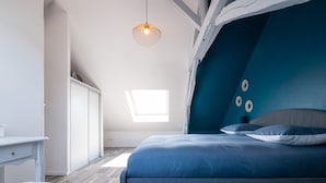 A bedroom with a bed, a desk, and a chair. There is a skylight above the bed and a hanging light fixture. - Chic Apartment Near City Center (Ecommoy)