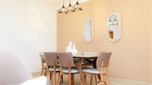 A dining area with a table and chairs, a candle on a side table, and two ornate mirrors on the wall. - Polo Heights -Sky Suites (Accra)