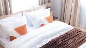 A neatly made bed with white and orange pillows, a brown blanket, and a wooden headboard. - Polo Heights -Sky Suites (Accra)