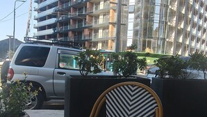 A glass table with a coffee cup, a patterned chair, and a view of a multi-story building with balconies. - Apartment with Sea View in New Boulevard of Batumi (Batumi)