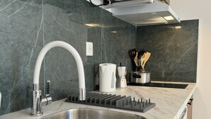 A modern kitchen with a stainless steel sink, a curved faucet, and a marble backsplash. - Apartment in Le Mans With Private Terrace (Le Mans)