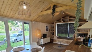 A modern kitchen with a wooden countertop, a sink, and a dining area with a round table and white chairs. - Tiny House Drents-Friese Wold with terrace and parking lot (Hoogersmilde)