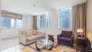 A modern living room with a beige sofa, a purple armchair, and a glass coffee table.