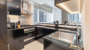 A modern kitchen with a stainless steel sink, black countertops, and a window with a city view.