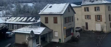 A building with a snow-covered roof, a courtyard, and a mountain in the background.
