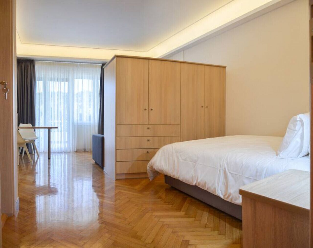 A bedroom with a bed, a desk, and a wardrobe.