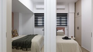 Un dormitorio con dos camas, paredes blancas y ventiladores de techo.