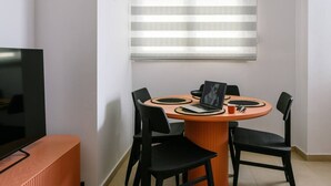 Un comedor con una mesa redonda, sillas negras y un ordenador portátil.
