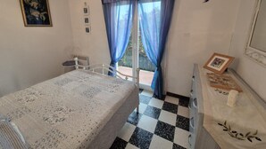 Un dormitori amb un llit, una petxina, una cadira i una finestra amb cortines.