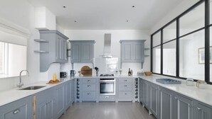 A modern kitchen with grey cabinetry, a central island, and a large window. - Luxurious 3-Bedroom Notting Hill (Greater London)