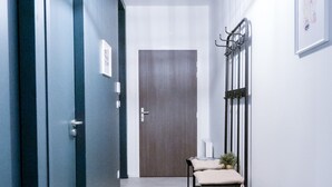 A narrow hallway with a bench, a door at the end, and a hanging light fixture. - Urban Calm - Bright & Modern Stay (Le Mans)