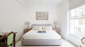 Une chambre bien rangée, avec un grand lit, des tables de chevet, un bureau et une chaise.