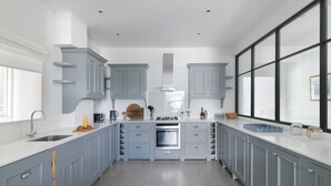 Une cuisine moderne avec des meubles gris, un îlot central et une grande fenêtre qui laisse entrer la lumière naturelle.