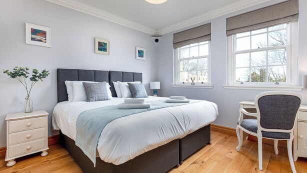 A bedroom with a large bed, bedside tables, a chair, and a window.