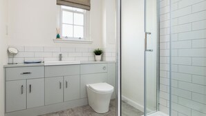 A bathroom with a toilet, sink, and shower area.